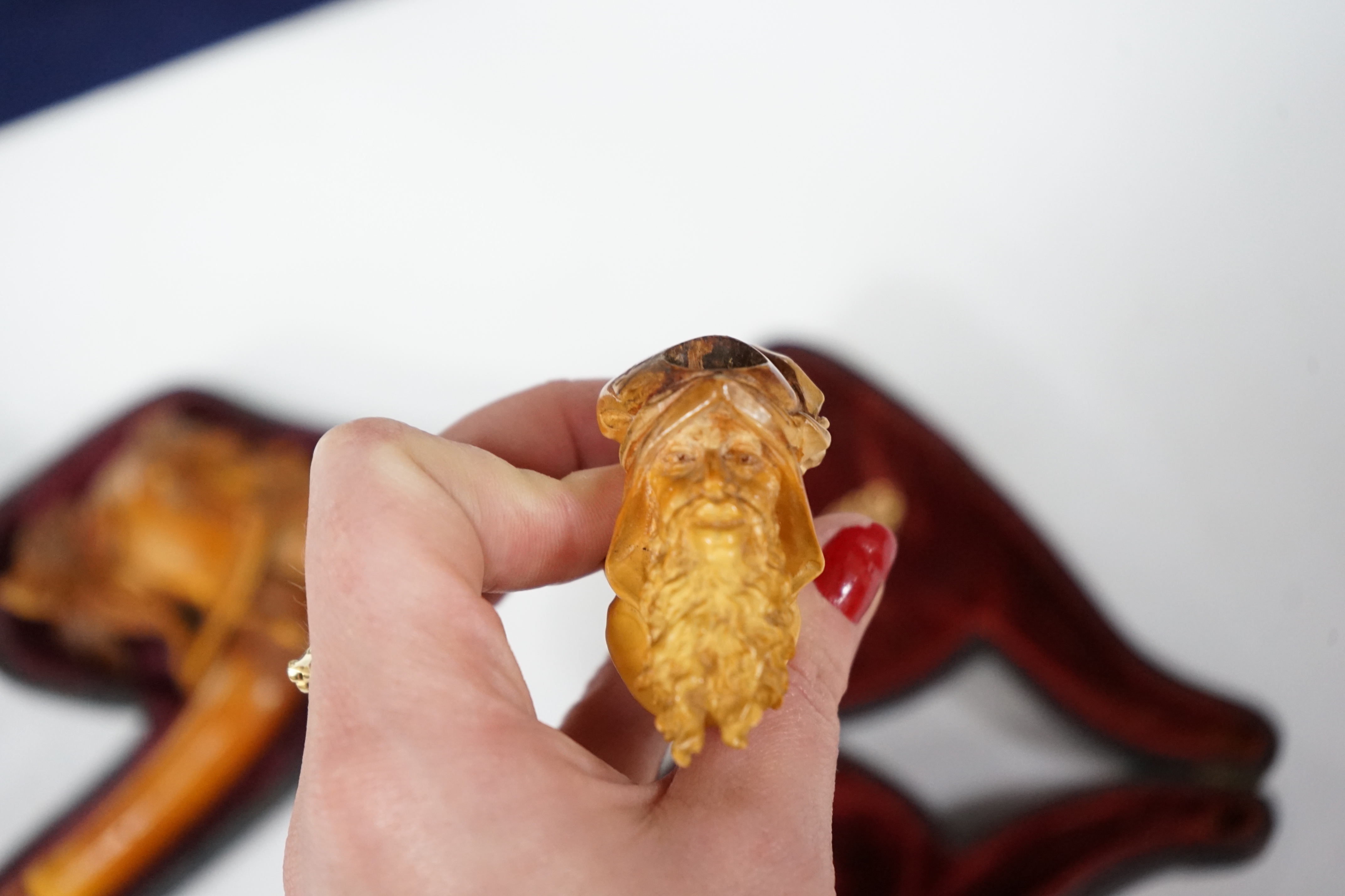 Two cased novelty Meerschaum pipes, their bowls modelled as an Arthurian knight and another a bearded man, both with amber mouthpieces, largest 16cm long
